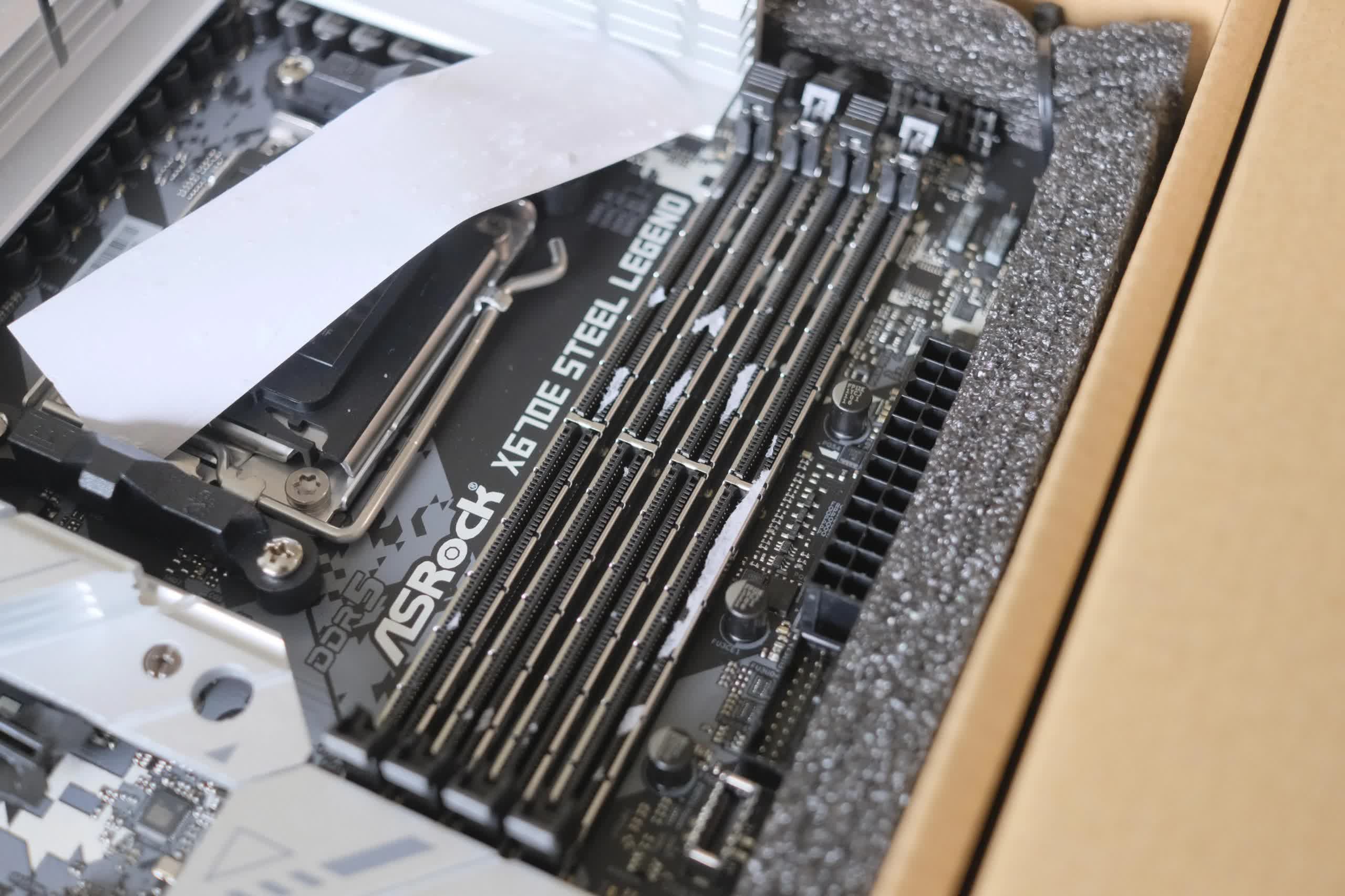 Asrock will send you a replacement motherboard if you can't get the stickers out of your DIMM sockets