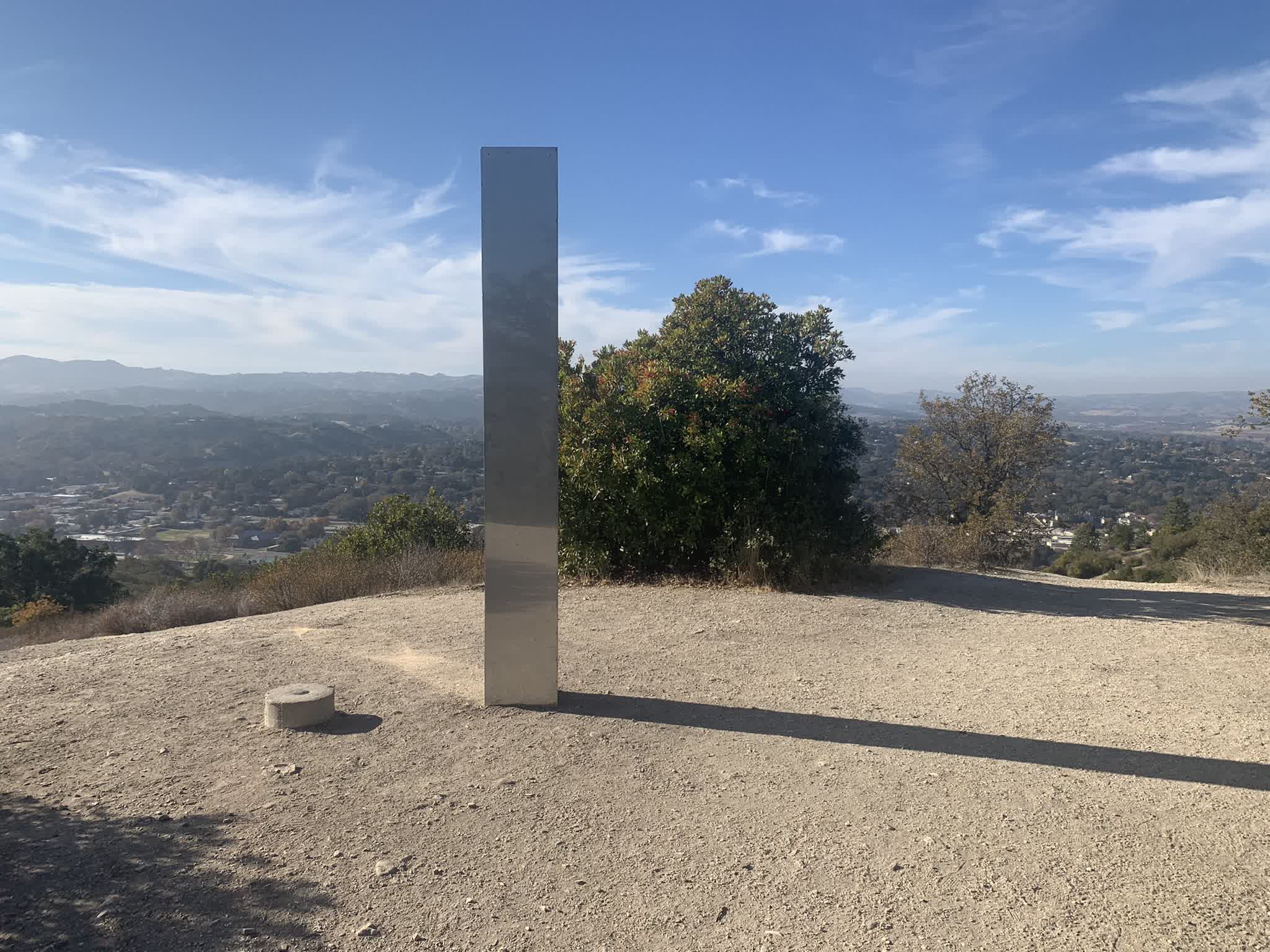 A third metal monolith appears, this one in California